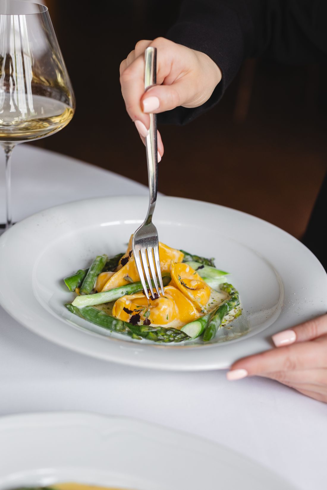 Prato de massa autoral servido com vinho branco