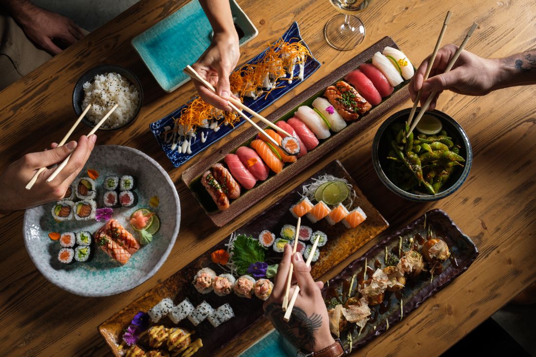 Mesa compartilhando combinados de sushi