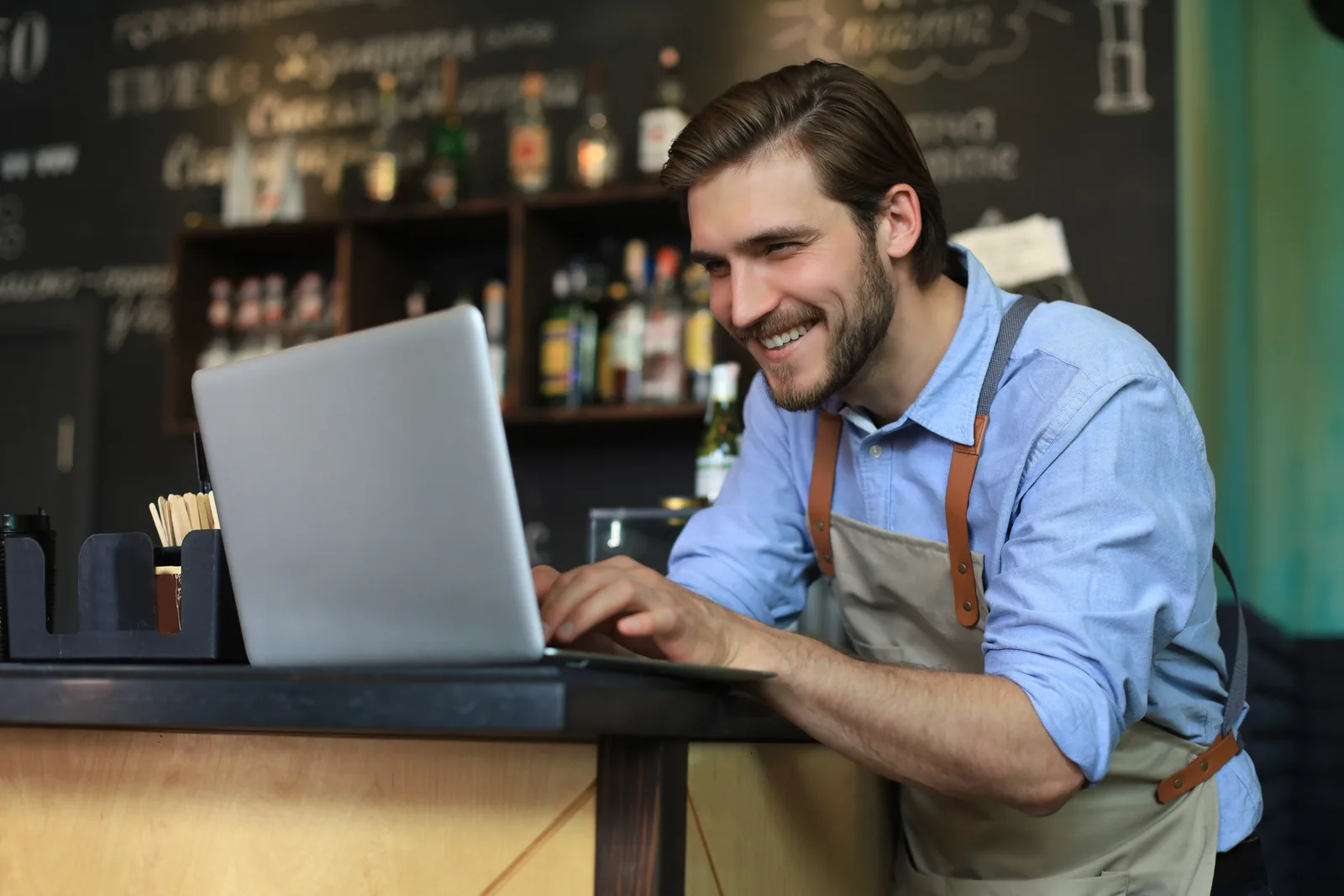 Gestor conferindo o sistema no notebook atrás do balcão
